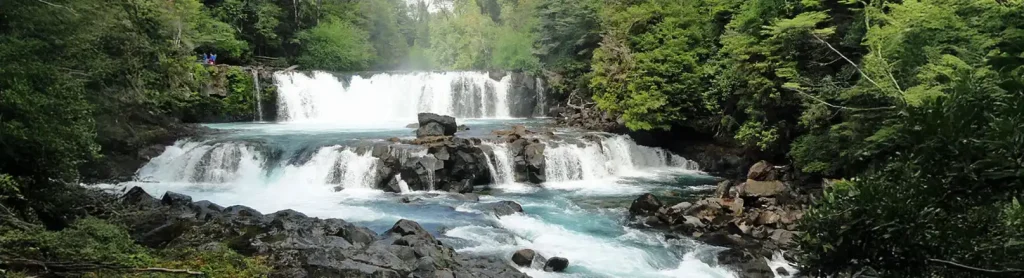 Cascada de aguas turquesa entre rocas y bosque nativo en la Reserva Biológica Huilo Huilo